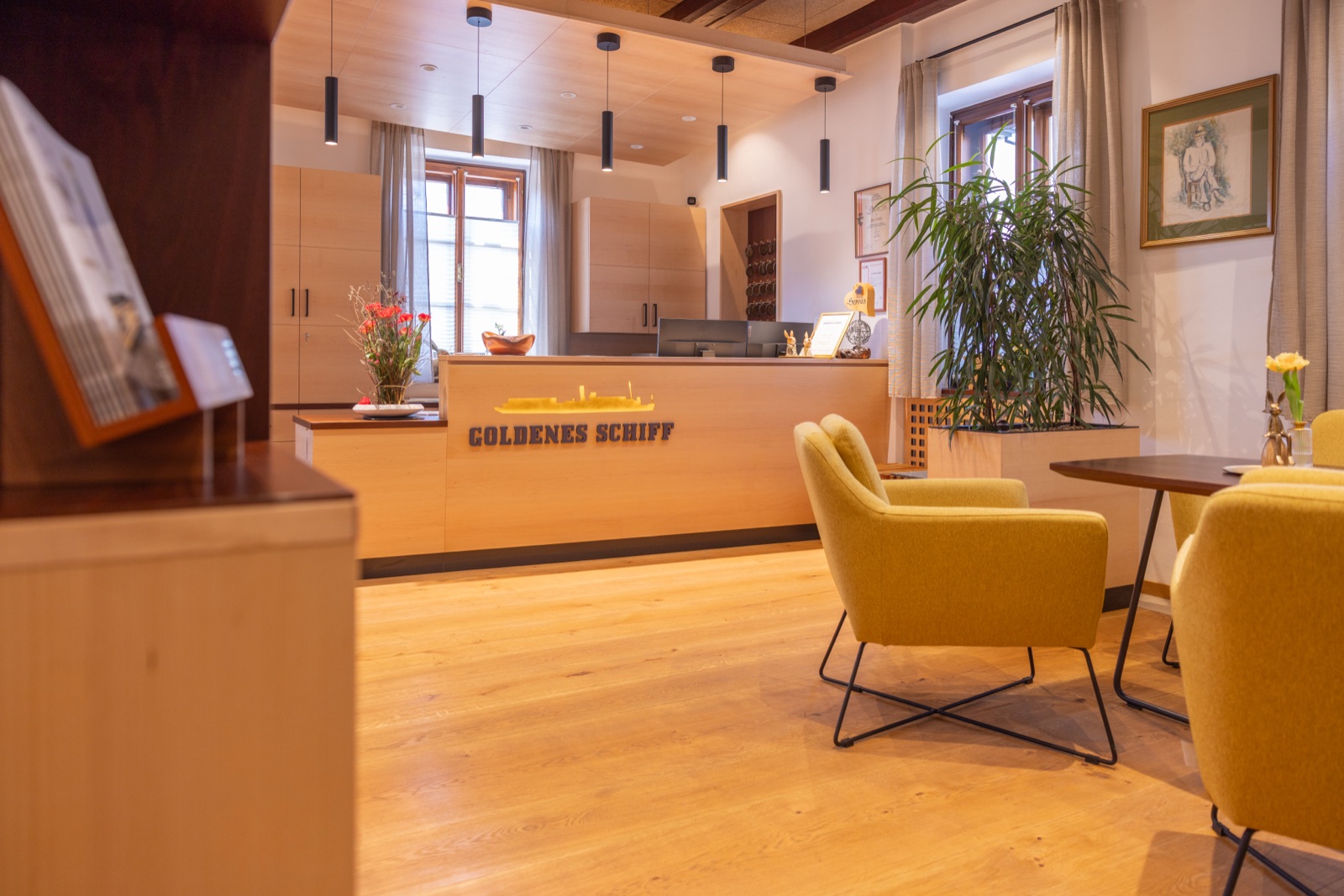 Empfangsbereich mit Rezeption und gelben Sesseln im Gasthof Goldenes Schiff